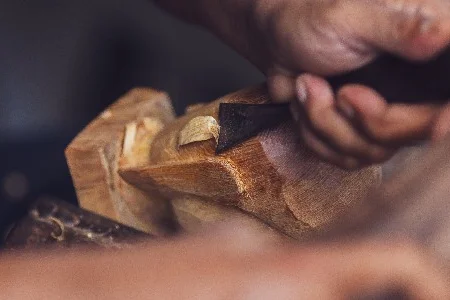 Person schnitzt Holz mit Meißel